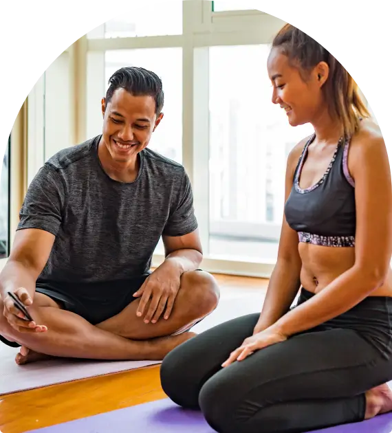 A man and woman stretching indoors, preparing for exercise.