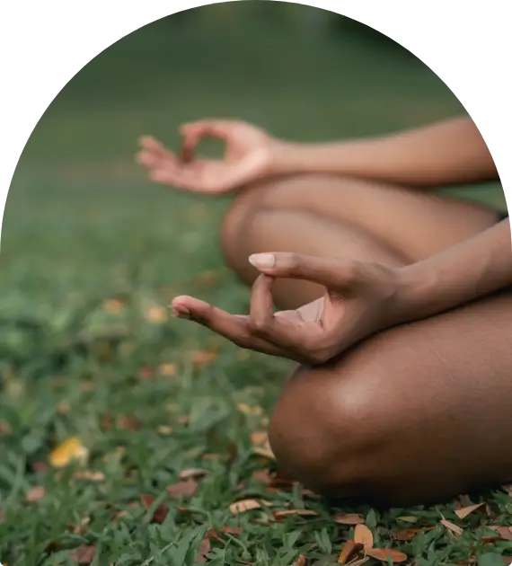 Person meditating outdoors with hands in a mudra position.